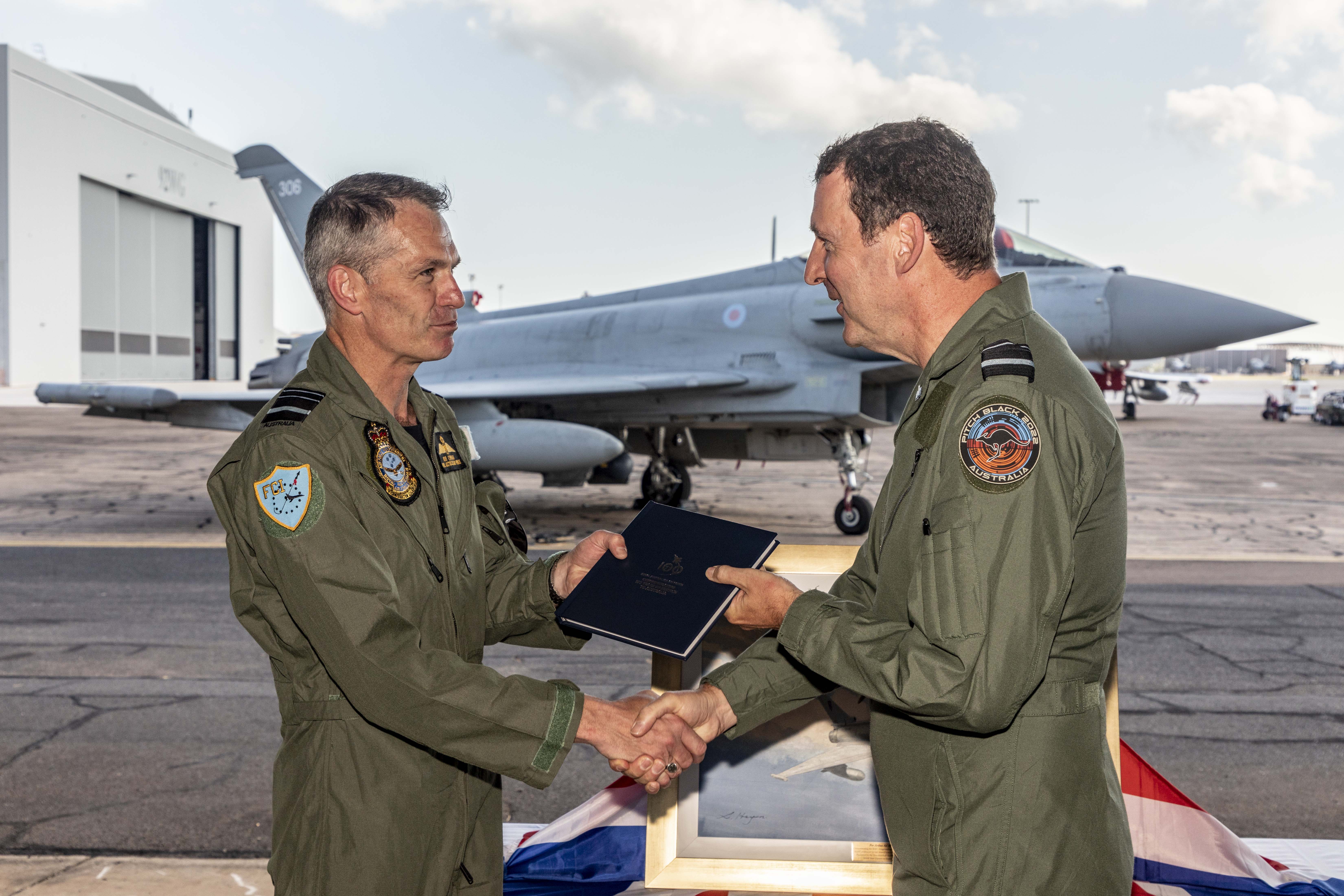 Image shows RAF Personnel shaking hands by a Typhoon on the airfield.